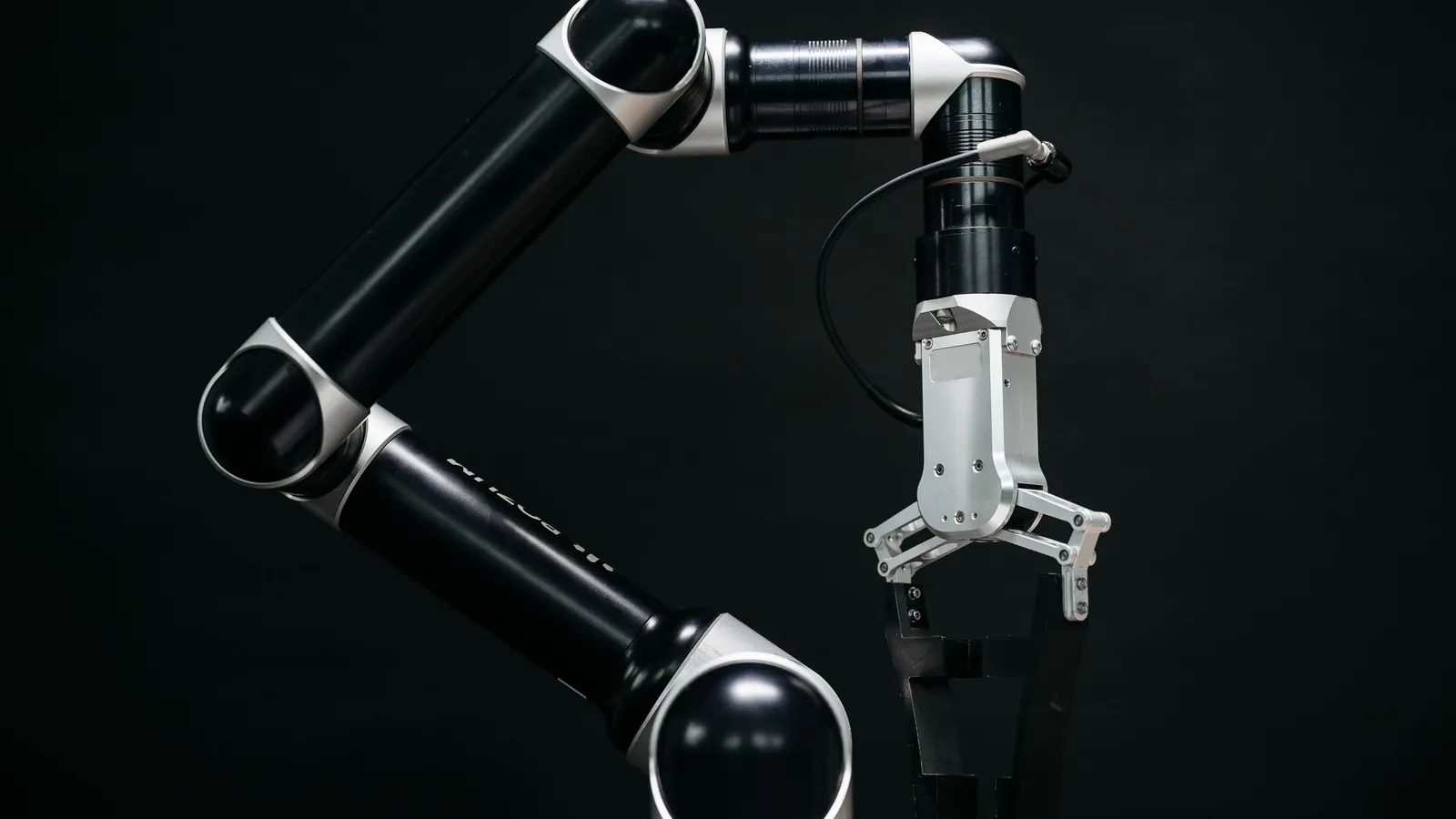 Roboterarm mit Greifer vor dunklem Hintergrund